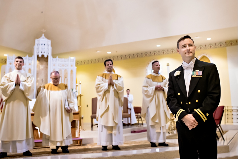 A groom waits at the end of the isle for his bride.